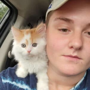 Alex, Surgical Assistant, with an orange and white kitten on his shoulder.