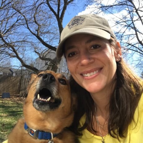 Cara, Certified Veterinary Technician, outdoors with her tan dog.