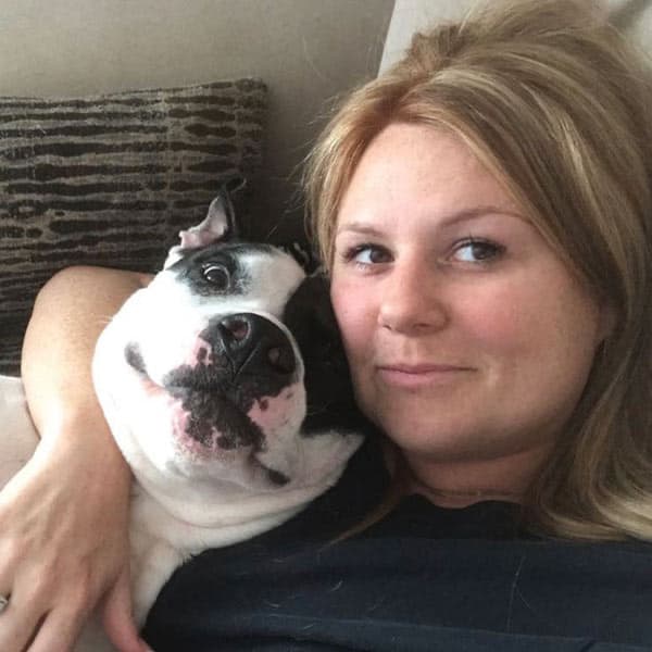 Jessica, Veterinary Assistant, curled up beside her black and white dog.