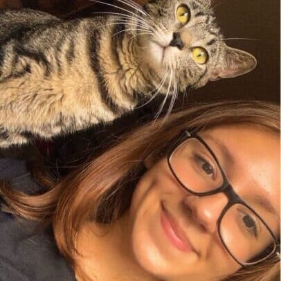 Meagan, Certified Veterinary Technician, with her tabby cat draped over her shoulder.