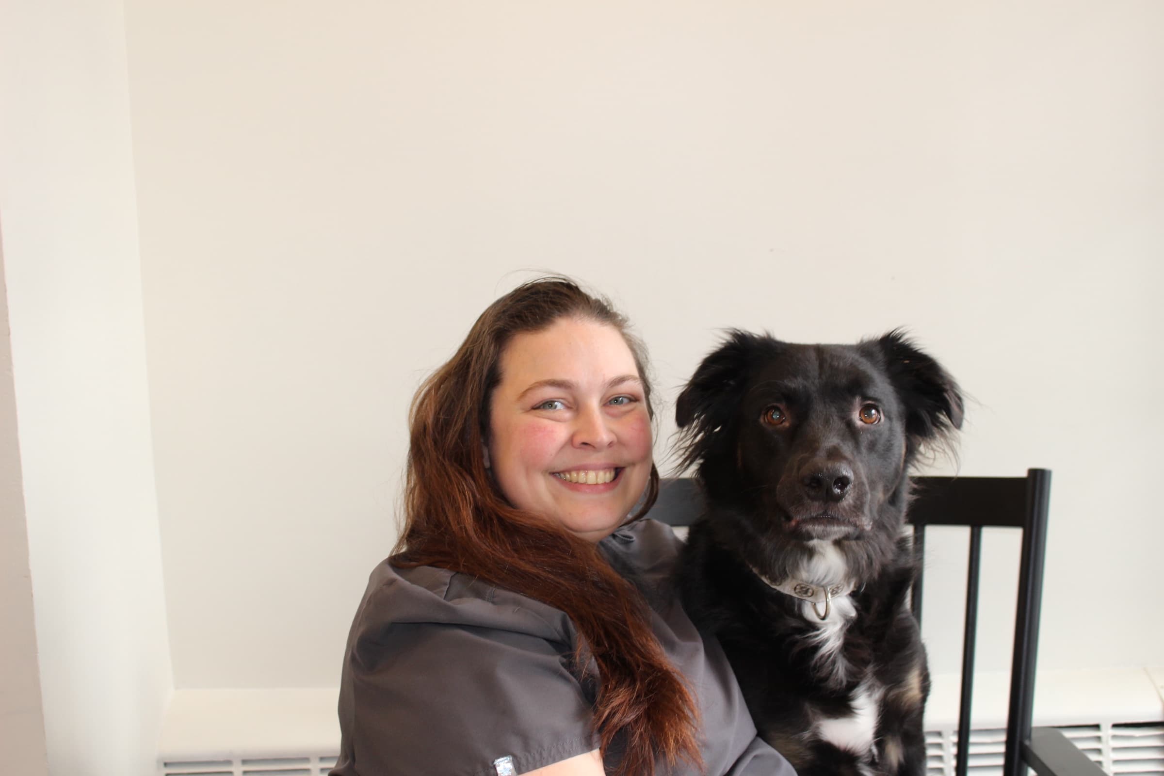 Shyra, Veterinary Assistant, smiling beside her black and white dog Zazu.
